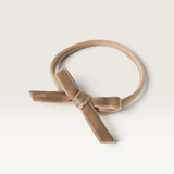 House of Holabox Snuggle Hunny baby headband in beige velvet with a petite bow on a soft stretch nylon elastic band
