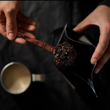 House of Holabox Somage 9 Spice Honey Fresh Chai being scooped with a copper measuring spoon from a black pouch