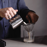 House of Holabox Somage 9 Spice Honey Fresh Chai being poured through a metal strainer into a glass