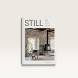 House of Holabox Still The Slow Home book cover featuring a rustic interior with a stone wall and wood stove