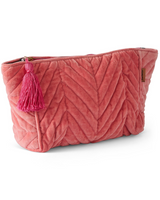 House of Holabox strawberry pink quilted velvet toiletry bag with a decorative tassel and zip closure.