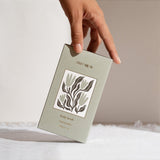 House of Holabox Stray Willow Green Smoothie body scrub box held by a hand against a neutral background
