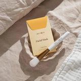 House of Holabox Stray Willow Golden Glow facial mask powder sachet with a white applicator brush in a ceramic bowl.