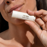 House of Holabox Stray Willow Mango Sorbet lip balm held by a woman with hydrated, glowing skin.