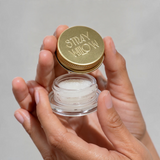 House of Holabox Stray Willow Peaches and Cream sugar lip scrub in a small glass jar with a gold lid held in hands