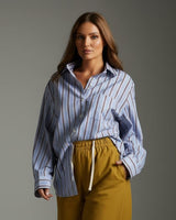 House of Holabox blue and brown striped cotton boyfriend shirt worn by a model with mustard yellow wide-leg pants.