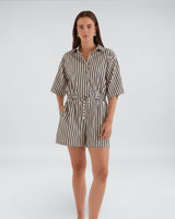 Model wearing a House of Holabox Ingrid striped cotton-blend playsuit with a collared neckline and tie waist.
