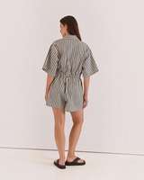 Back view of a woman wearing a House of Holabox Ingrid striped cotton-blend playsuit with a tie waist and collar.