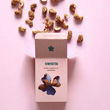 House of Holabox Sweeta honey roasted cashews in a pink box with loose nuts scattered on a light pink background