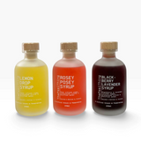 House of Holabox The Peel Thing syrup trio in lemon, rose, and blackberry lavender flavors in frosted glass bottles.