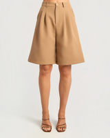 House of Holabox tan high-waisted Bermuda shorts featuring a longline tailored silhouette, front pleats, and belt loops.