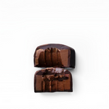 House of Holabox vegan dark chocolate truffle cut in half showing a smooth, rich ganache center.