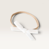 House of Holabox Snuggle Hunny baby headband featuring a white velvet petite bow on a soft stretch nylon elastic band