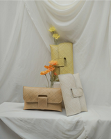 House of Holabox Willow envelope clutches in off-white, tan, and yellow, handwoven from pandan leaves with floral decor.
