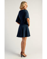 Navy Belle Wrap Dress featuring elegant bell sleeves and a flattering layered frill hem, worn with black heels.