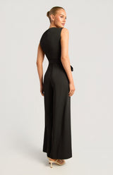 Jasmine Front Pleat Jumpsuit in black, featuring a sleeveless silhouette and a polished gold buckle detail.