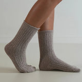 Gray knitted socks worn by a person on a light background