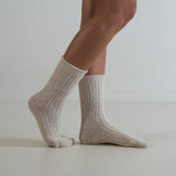 Beige socks worn by a person on a plain background