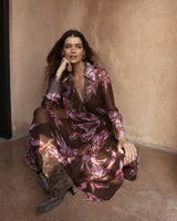 Model wearing a dark floral print Isla wrap dress in sheer viscose with a collared neckline and self-tie waist.