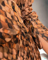Close-up of the Isla wrap dress in an exclusive brown and orange print, featuring fluid fabric and buttoned sleeve cuffs.