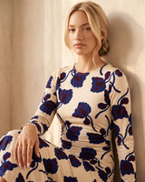 Fitted jersey dress with a boat neckline, gathered waist, and blue floral print on a cream background.