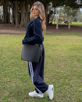 Woman wearing navy Jamie joggers with heart-patterned side stripes, paired with a navy sweater and white sneakers.