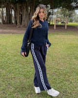 Woman wearing navy Jamie joggers with heart-patterned side stripes, paired with a matching navy cardigan and sneakers.