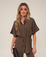 Woman wearing a brown cotton-nylon drawstring shirt with short sleeves and a cinched waist.