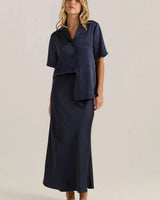 Navy midi-length bias-cut slip skirt with an elasticated waistband, styled with a matching button-down shirt.