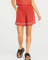 Relaxed-fit terracotta cotton shorts with an elastic drawstring waist, side pockets, and white embroidered hem detailing.