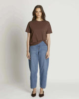 Model wearing a chocolate brown cotton-blend Jen Tee with a side-knot detail, paired with blue denim jeans.