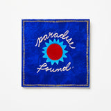 Blue fabric square with 'Paradise Found' text and sun design on a white background