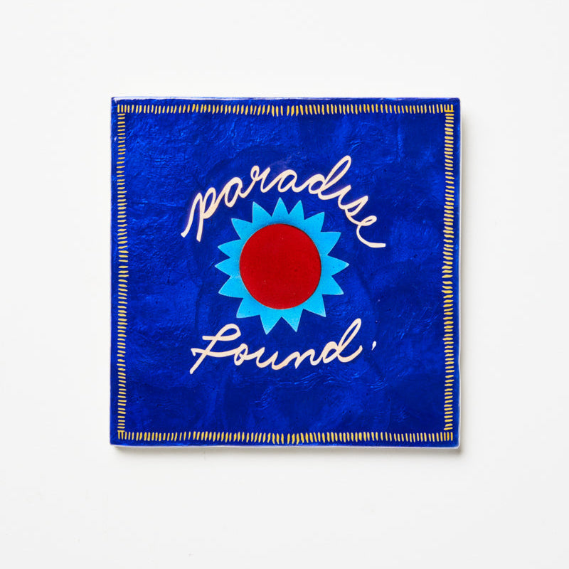 Blue fabric square with 'Paradise Found' text and sun design on a white background