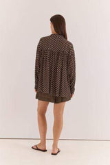 Woman wearing a relaxed-fit, long-sleeve Joy Shirt in brown viscose with a white polka dot print.