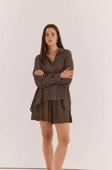 Woman wearing a relaxed-fit, long-sleeve brown viscose shirt with a white polka dot pattern and button-down collar.