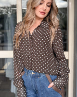 Woman wearing a relaxed-fit, brown long-sleeve viscose shirt with white polka dots, a collar, and button-down front.