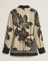 Beige and black floral print collared shirt with contrast trim and an adjustable back waist tie.