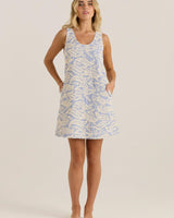 Blue and white embroidered shift dress with wide straps and side pockets on a model.