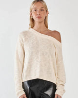 Model wearing a cream-colored, 100% cotton textured knit sweater with a relaxed fit and an asymmetric neckline.