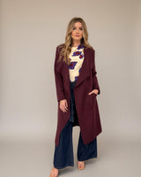 Wine-colored relaxed fit coatigan with an open front, long sleeves, and side pockets worn over a floral top and jeans.