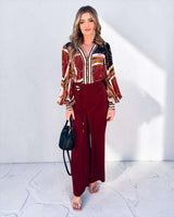 Lauren blouse in a burgundy and gold chain print rayon with long sleeves, paired with matching wide-leg trousers.