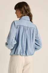 Model wearing a light wash denim bubble jacket with gathered back detailing, stand collar, and puff sleeves.