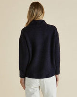 Navy blue mock neck knit jumper with ribbed cuffs and hem, shown from the back on a model with light hair.