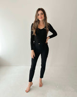 Woman wearing black Luella stretch jeans with a sleek, mock-pocket design and a fitted black long-sleeve top.