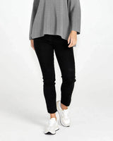 Black Luella stretch jeans with a sleek, mock-pocket design paired with white sneakers and a grey top.