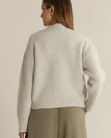 Back view of a woman wearing a relaxed-fit, snow marle white fluffy knit jumper with ribbed cuffs and hem.