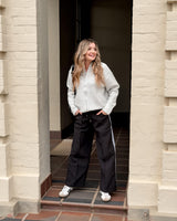 Woman wearing black Maddison joggers with a relaxed fit, elasticated waistband, and side stripe detail.