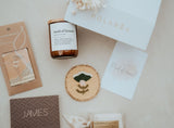 Collection of personalized items including a candle, coaster, and cards on a light surface with 'Holabox' branding.