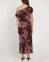 Back view of a brown one-shoulder maxi dress in viscose yoryu with a pink and red floral print and gathered waist.