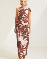 One-shoulder maxi dress in a brown and cream floral print with side ruching and a tie-shoulder detail.